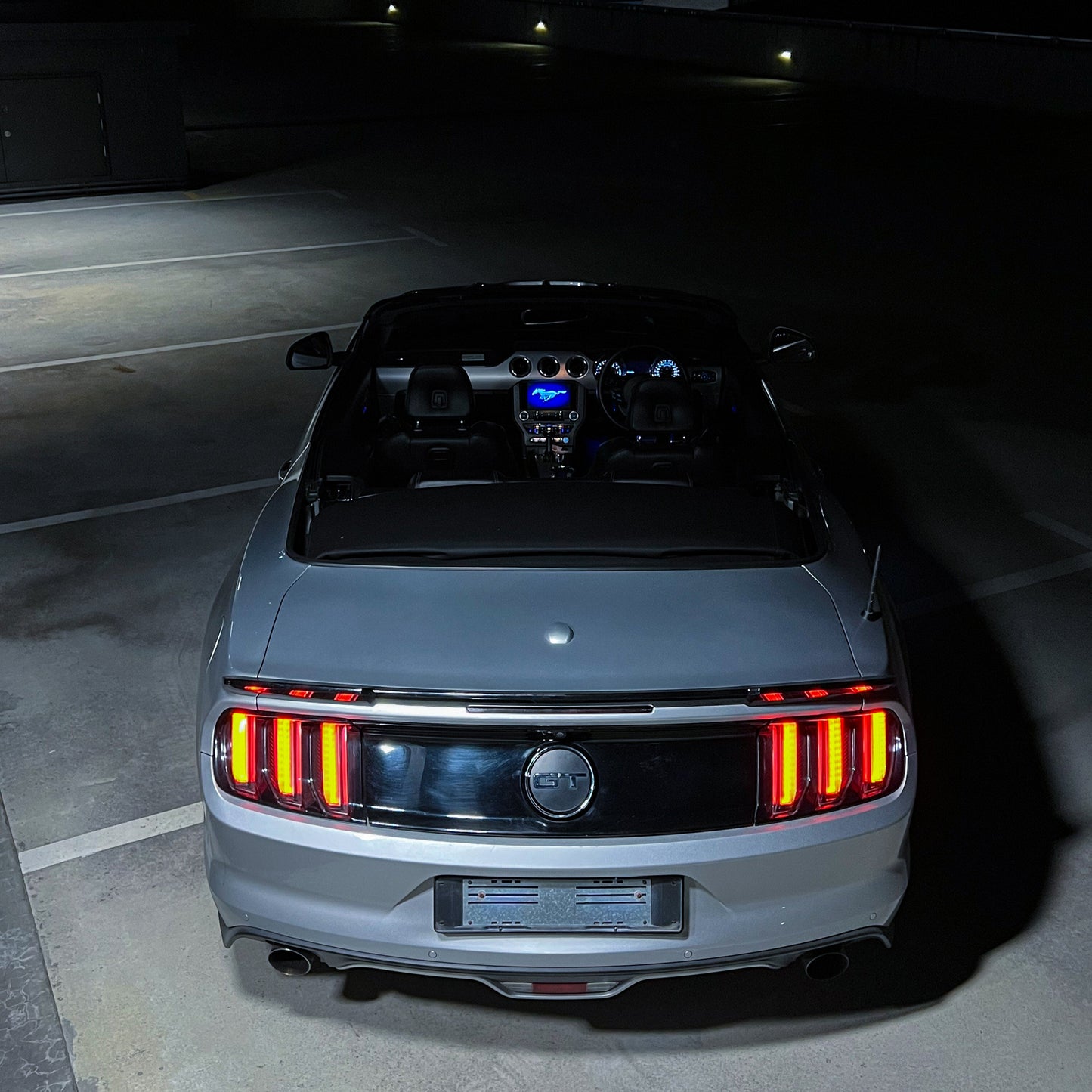 Back view of a car with illuminated taillights in a dark setting
