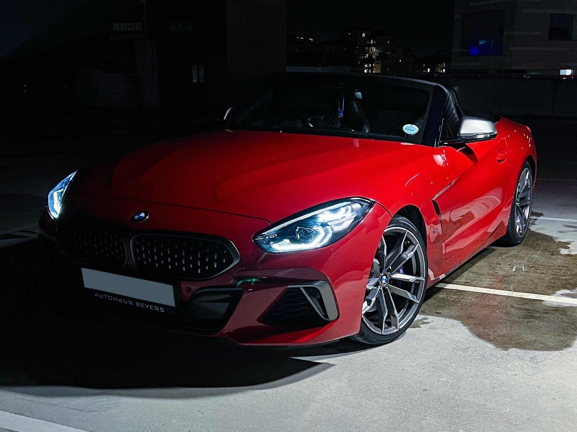 Red BMW Z4 convertible parked on a dark street at night.