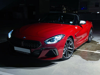 Red BMW Z4 convertible parked on a dark street at night.