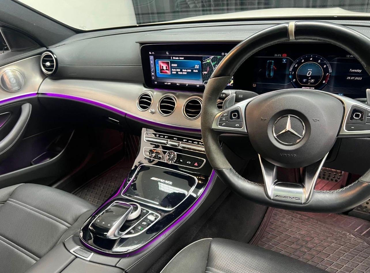 Car interior with steering wheel and dashboard featuring a Mercedes logo.